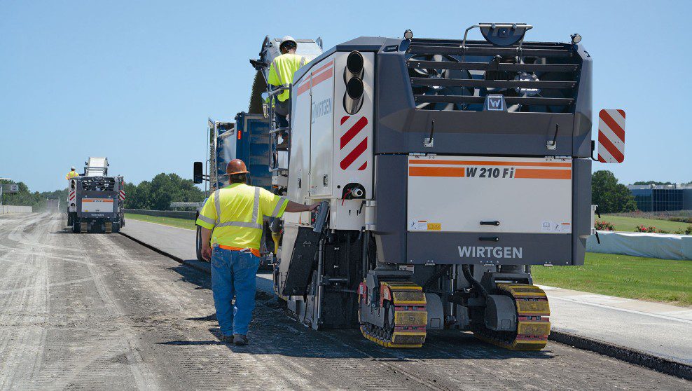 Wirtgen cold milling machine cutting asphalt with ground man assisting